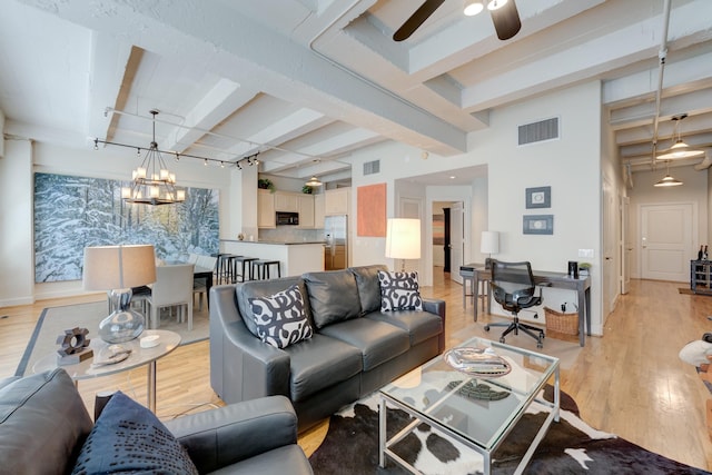 living room featuring ceiling fan with notable chandelier, beam ceiling, and light hardwood / wood-style flooring