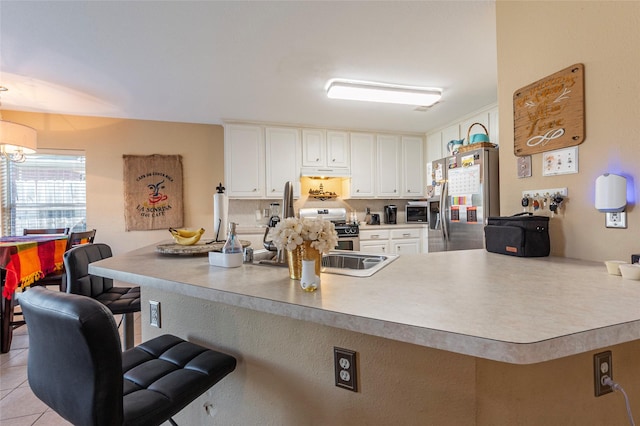 kitchen with kitchen peninsula, white cabinetry, light tile patterned flooring, and stainless steel appliances