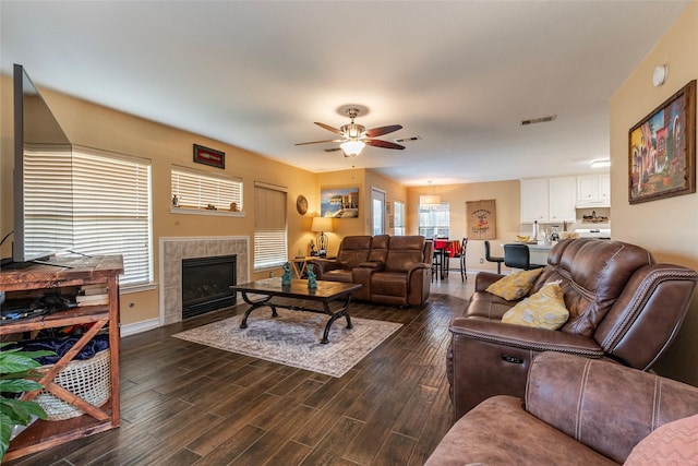 living room with a tile fireplace and ceiling fan