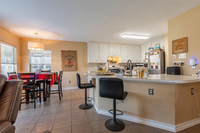 kitchen featuring an inviting chandelier, light tile patterned floors, decorative light fixtures, white cabinetry, and stainless steel appliances