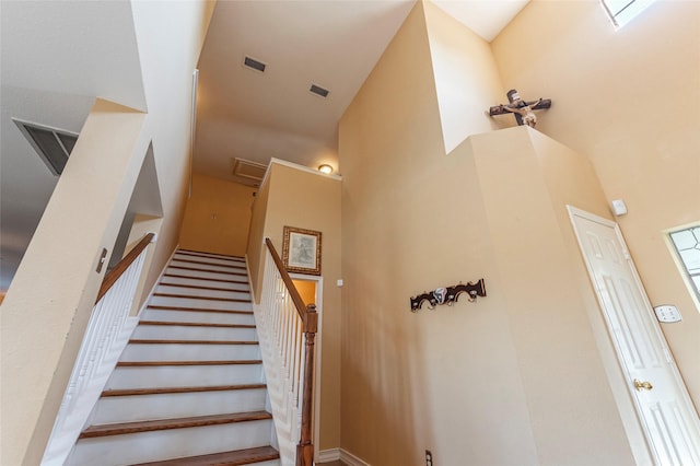 stairway featuring a towering ceiling