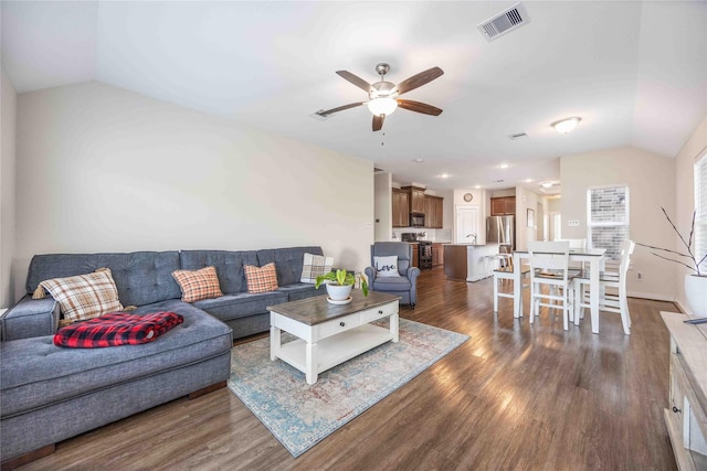 living area featuring lofted ceiling, visible vents, dark wood-style flooring, and ceiling fan