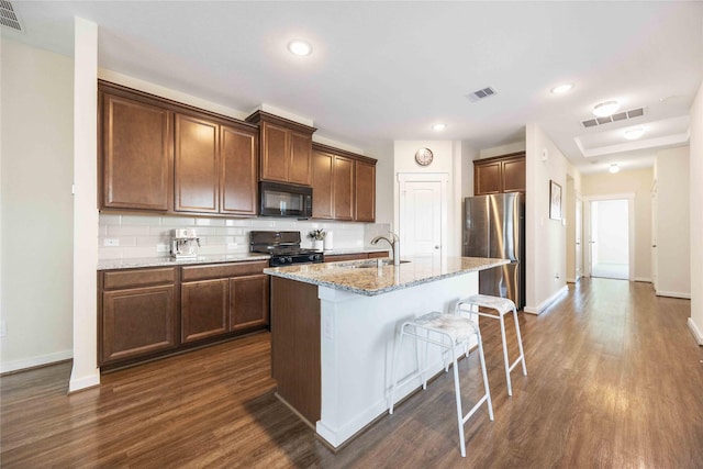 9211 Melmack Dr, Rosharon, TX 77583 - kitchen featuring black appliances, a sink, baseboards, a kitchen bar, and dark wood-style flooring