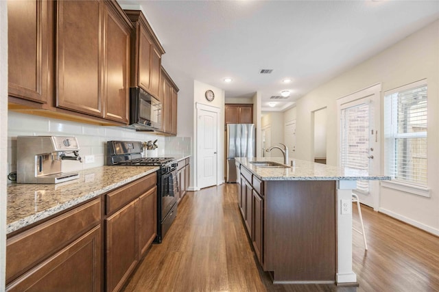 kitchen featuring decorative backsplash, black appliances, dark wood-style flooring, and a sink