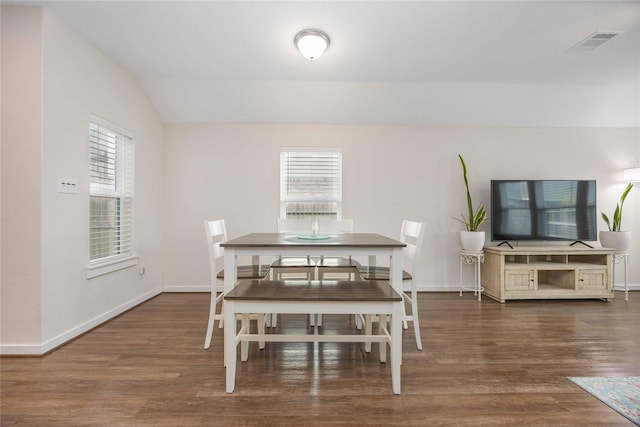 dining space with lofted ceiling, wood finished floors, visible vents, and baseboards