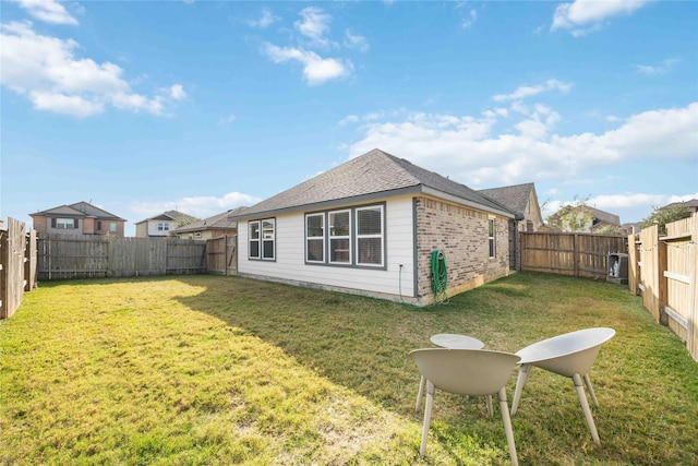 back of property with a lawn, a fenced backyard, and brick siding