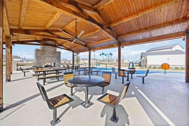 view of patio featuring ceiling fan, an outdoor stone fireplace, and a gazebo