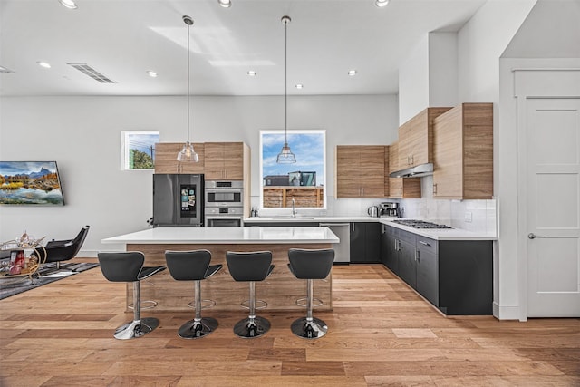 kitchen featuring a breakfast bar area, a center island, hanging light fixtures, and stainless steel appliances