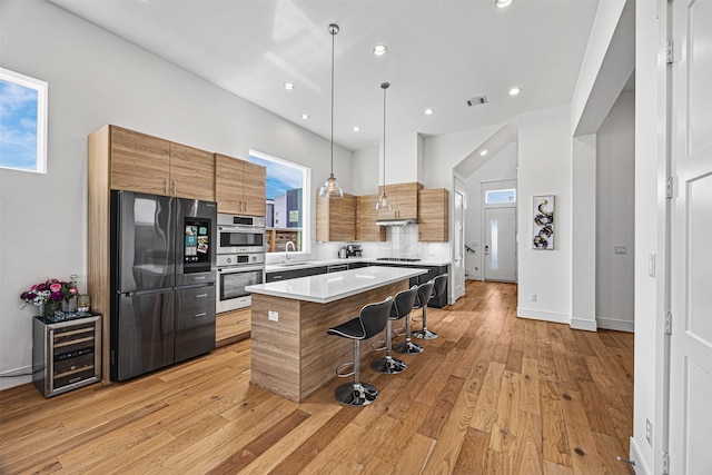 kitchen featuring a center island, sink, hanging light fixtures, stainless steel appliances, and a kitchen bar