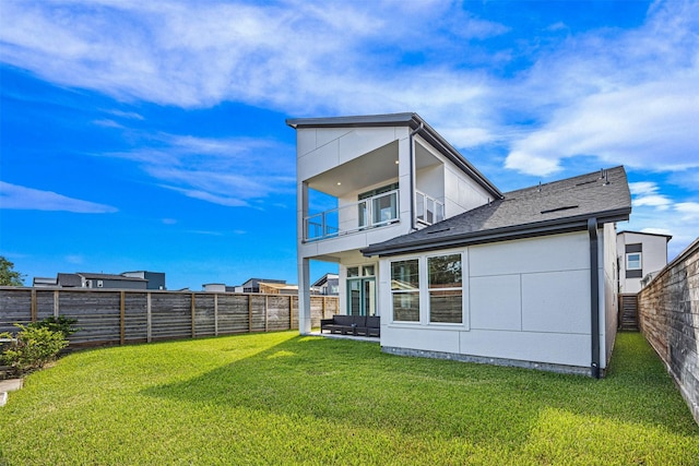 rear view of house with a lawn and a balcony