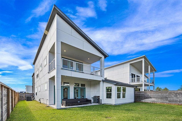 rear view of property with an outdoor living space, a balcony, a patio area, and a lawn