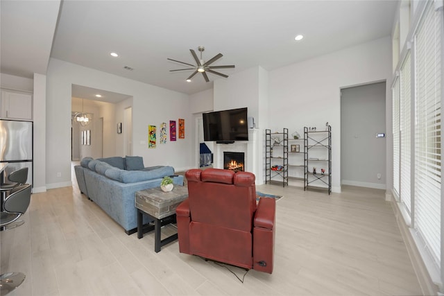 living room featuring ceiling fan with notable chandelier and light hardwood / wood-style flooring