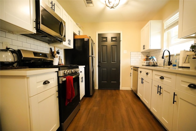 kitchen with stainless steel appliances, dark hardwood / wood-style flooring, white cabinetry, and tasteful backsplash