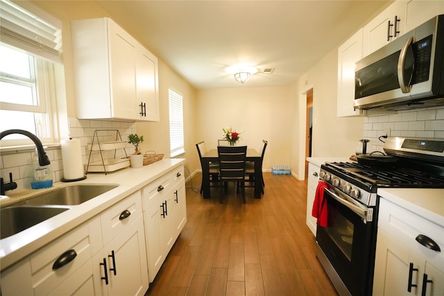 kitchen featuring stainless steel appliances, decorative backsplash, dark hardwood / wood-style floors, sink, and white cabinetry