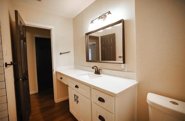 bathroom with toilet, vanity, and hardwood / wood-style flooring