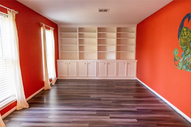 spare room with dark hardwood / wood-style flooring and built in features