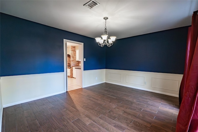 spare room featuring an inviting chandelier and dark wood-type flooring