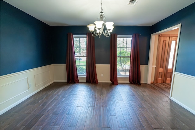 spare room featuring dark hardwood / wood-style floors and an inviting chandelier