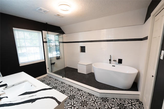 bathroom featuring lofted ceiling, tile patterned floors, sink, separate shower and tub, and a textured ceiling