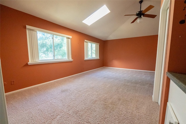 carpeted empty room featuring ceiling fan and lofted ceiling with skylight