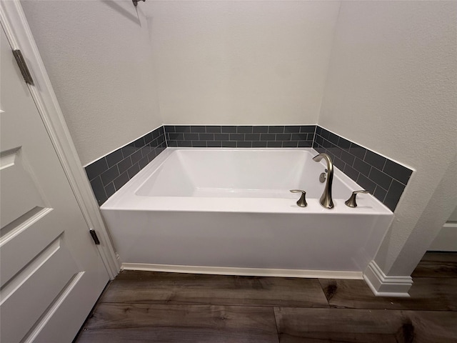 bathroom with a washtub and wood-type flooring