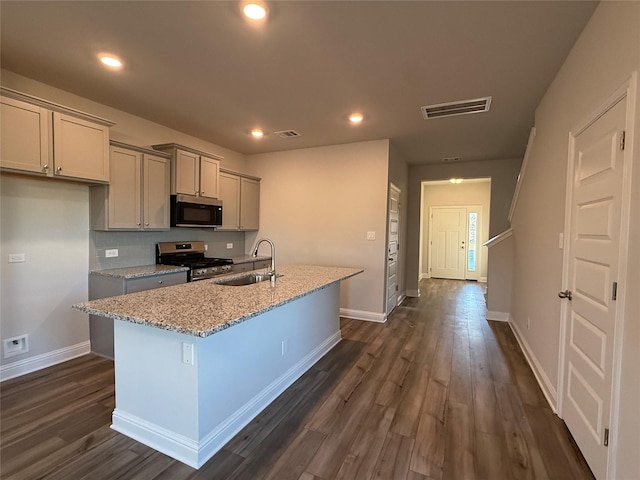 kitchen featuring light stone countertops, gray cabinetry, stainless steel appliances, sink, and an island with sink