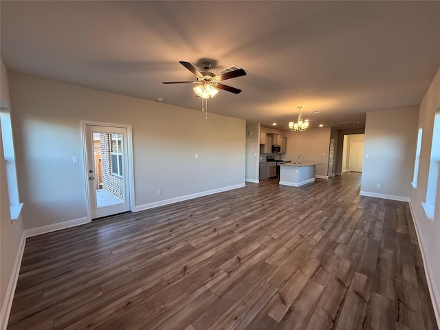 unfurnished living room with ceiling fan with notable chandelier and dark hardwood / wood-style floors