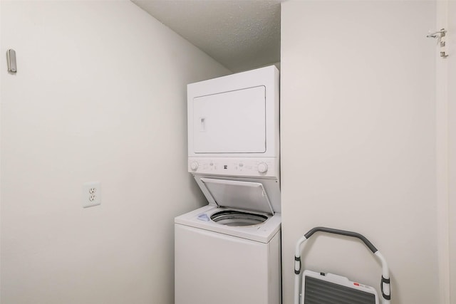 laundry area featuring a textured ceiling and stacked washer / drying machine