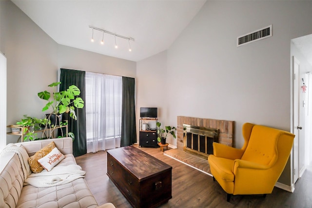 living room featuring dark hardwood / wood-style floors, rail lighting, and a brick fireplace