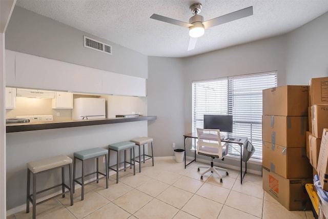 tiled office featuring ceiling fan and a textured ceiling