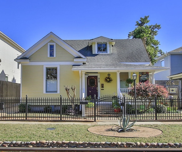 view of front of property with a porch, a fenced front yard, and a front yard