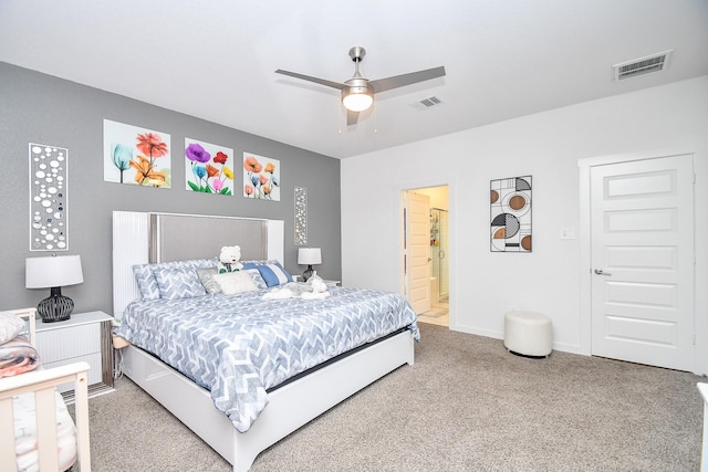 carpeted bedroom with ensuite bath and ceiling fan