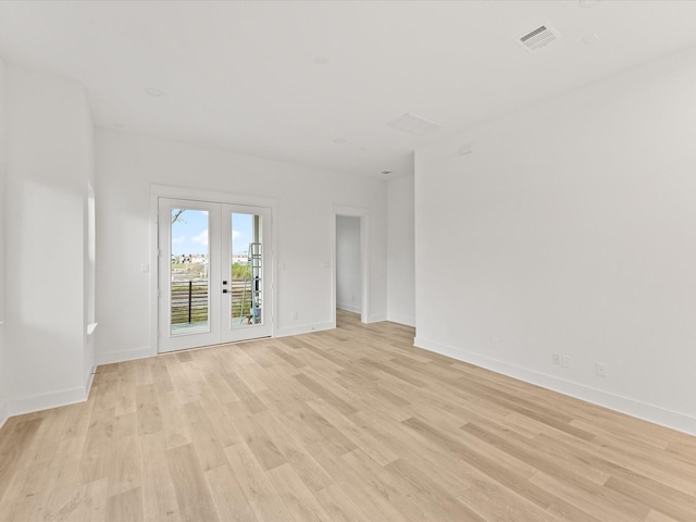 spare room featuring french doors and light hardwood / wood-style floors