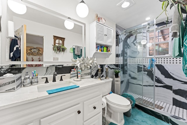 bathroom with vanity, a shower with door, and toilet