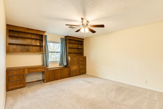 interior space with ceiling fan, light colored carpet, and built in desk