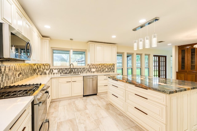 kitchen featuring decorative backsplash, sink, pendant lighting, and appliances with stainless steel finishes