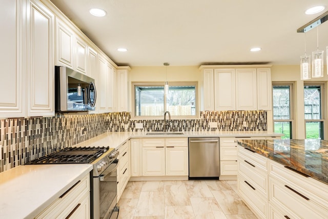 kitchen featuring backsplash, hanging light fixtures, sink, dark stone countertops, and appliances with stainless steel finishes