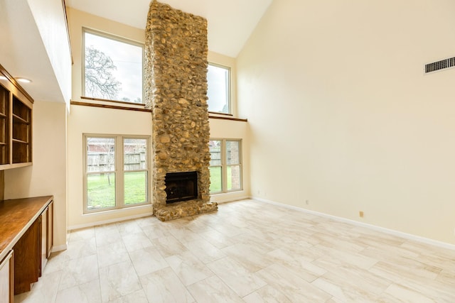 unfurnished living room featuring a healthy amount of sunlight, a stone fireplace, and high vaulted ceiling