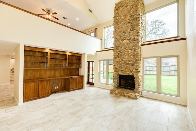 unfurnished living room with built in shelves, high vaulted ceiling, a stone fireplace, and ceiling fan