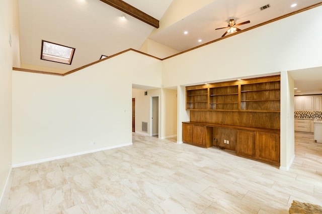 unfurnished living room featuring a towering ceiling, a skylight, built in shelves, ceiling fan, and beamed ceiling