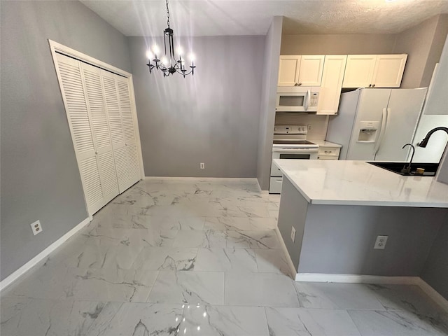 kitchen featuring white appliances, sink, a notable chandelier, white cabinetry, and hanging light fixtures