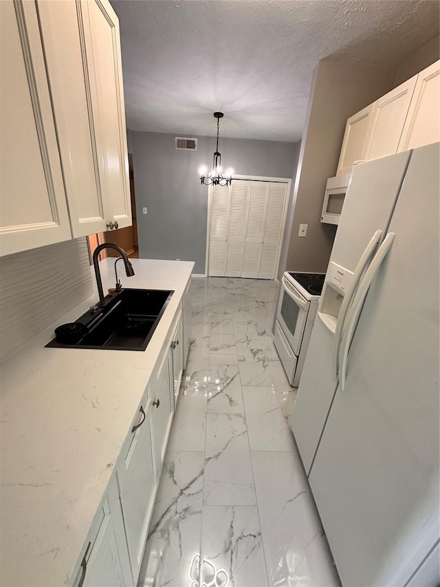 kitchen featuring pendant lighting, white appliances, an inviting chandelier, sink, and white cabinetry