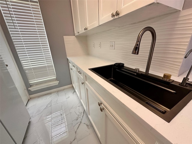 kitchen featuring white cabinets, decorative backsplash, and sink