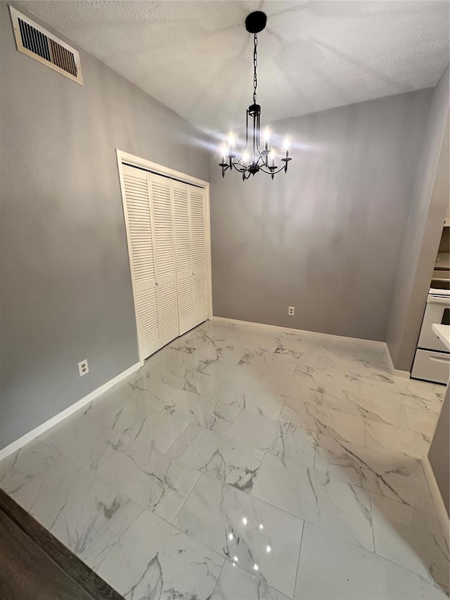 unfurnished dining area with a notable chandelier and a textured ceiling