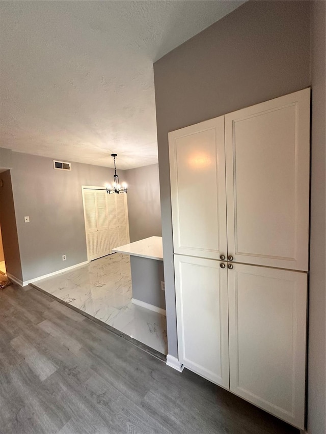 interior space featuring hardwood / wood-style flooring, a textured ceiling, and an inviting chandelier