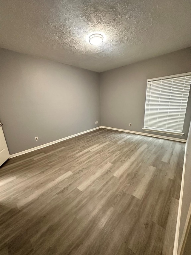 unfurnished room with hardwood / wood-style floors and a textured ceiling