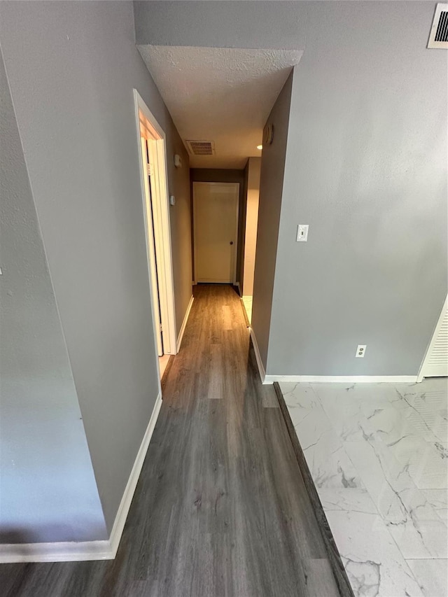 hall featuring wood-type flooring and a textured ceiling