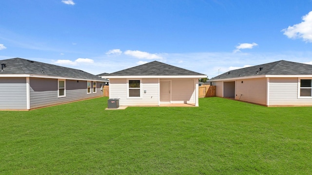 rear view of property with central air condition unit and a lawn