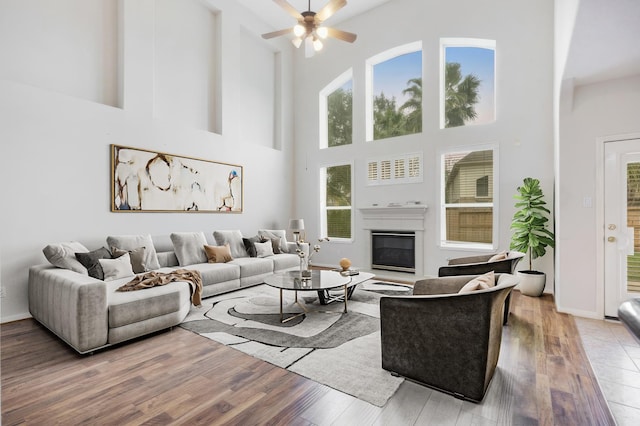 living room featuring ceiling fan, wood-type flooring, and a high ceiling