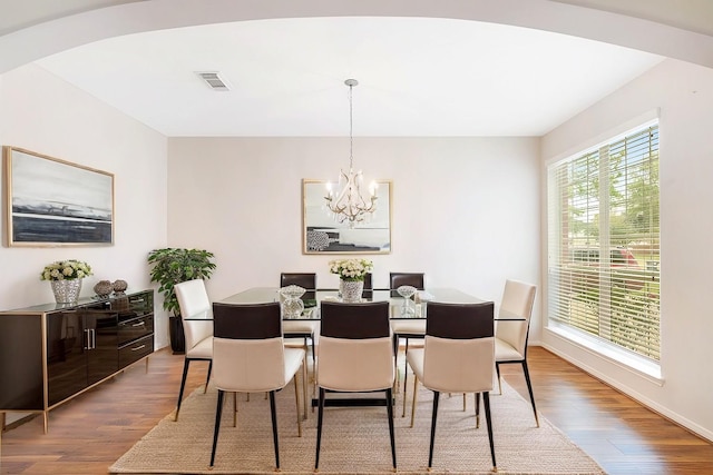 dining area with wood-type flooring and an inviting chandelier